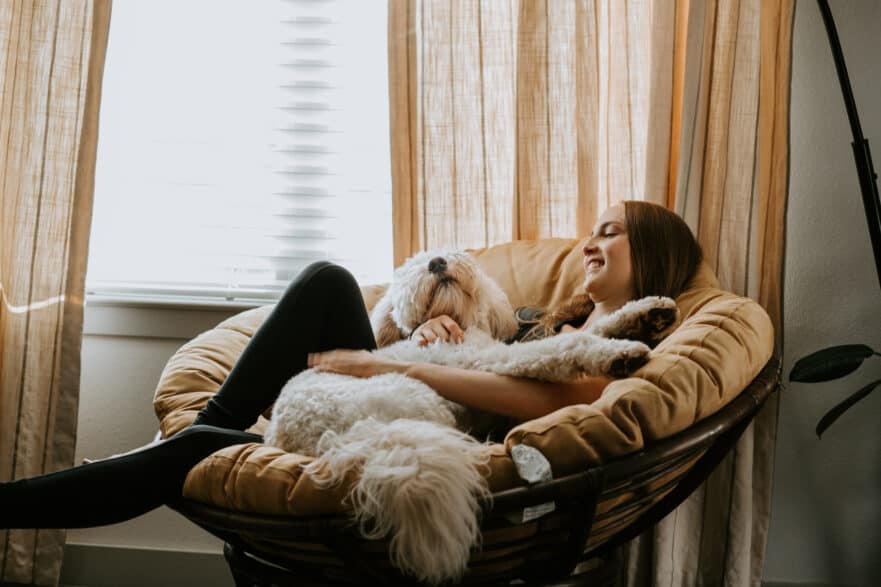 woman relaxing in a chair by the window at home with her dog