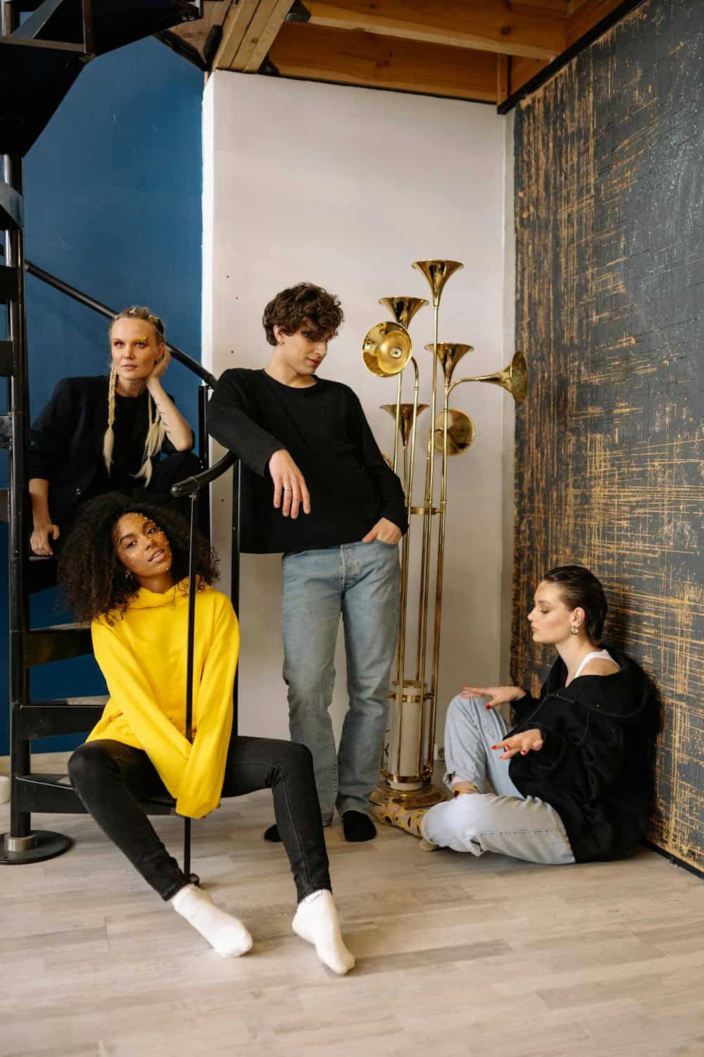 young adults posing on a staircase and in front of a brass floor lamp