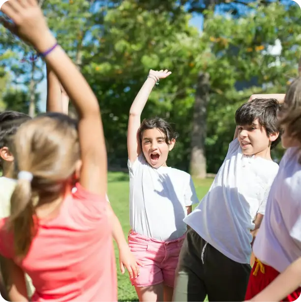 group of kids raising their hands with trees and grass on the background