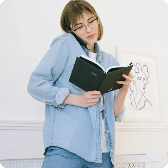 a lady reading a book while her phone is on her ear