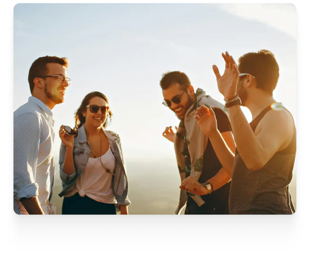 a group of friends smiling and talking to each other with the sun in the background