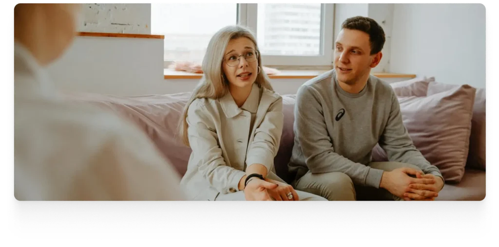 a man and a woman sitting on a sofa, talking to a therapist