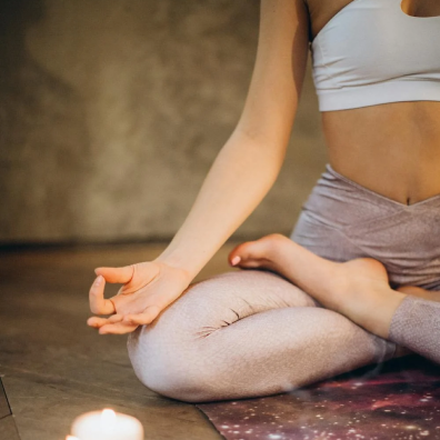 woman sitting in crosslegged yoga position with hands outstretched and palms facing up - thumbs touching index finger to form an o