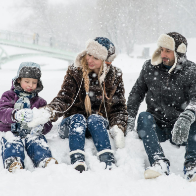 family playing in the snow in their winter attire