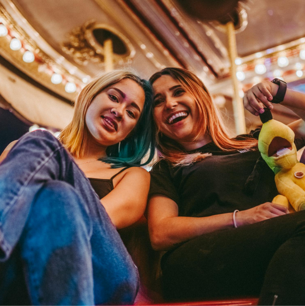 2 women in a concert hall smiling for a picture that is being taken from an angle near the ground