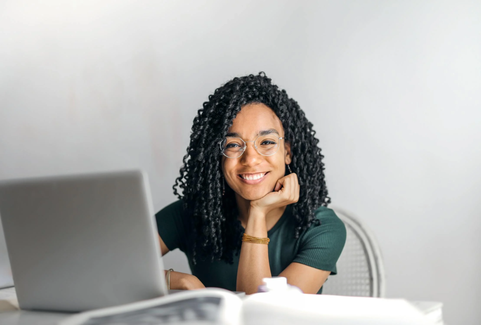 woman smiling while looking at a laptop screen (while doing online therapy)