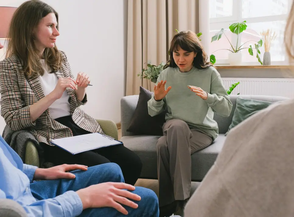 Older woman talking to 2 adults (a man and a woman) during a therapy session