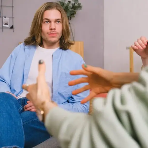 a man and woman with crossed hands sitting on a couch during a therapy session