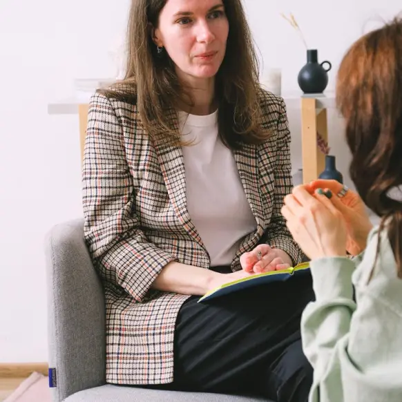 the back of a therapists head in the foreground with a man and woman sitting on a couch across from her during a therapy session 