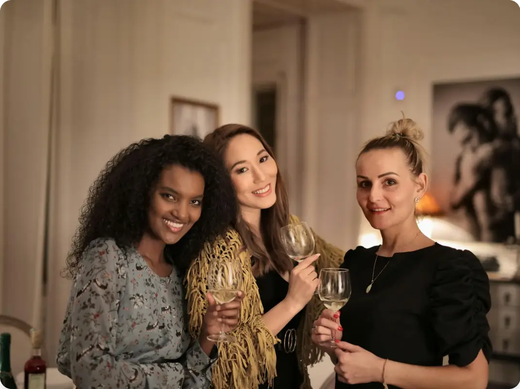 three ladies smiling with a glass of whine on their hands