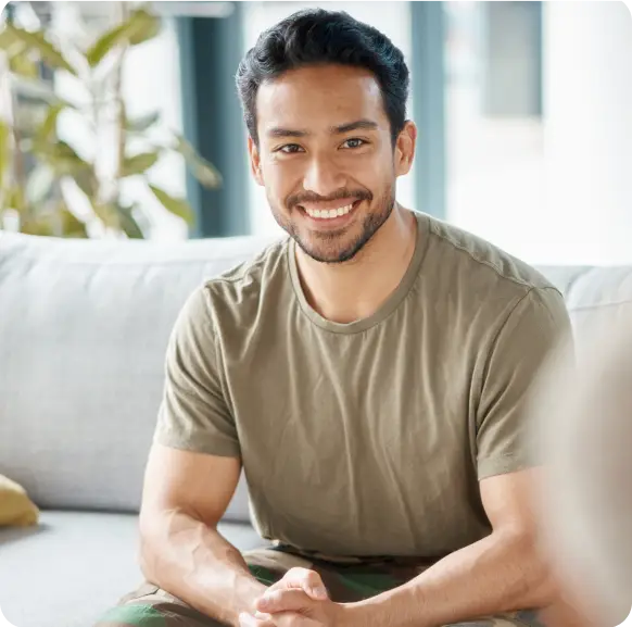 a man wearing brown shirt sitting on a couch