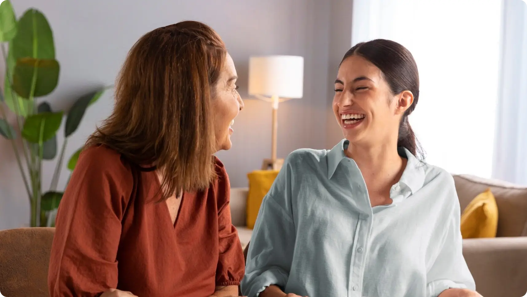 2 women sitting next to each other with coffee and pens in their hands