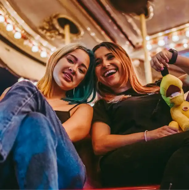 two women sitting on a carousel